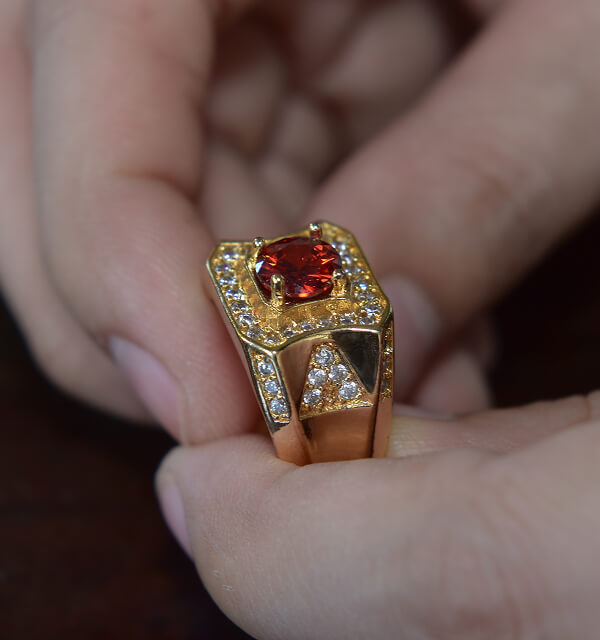 Gold ring with a red gemstone and diamond accents.