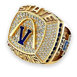 Close-up of a sparkling championship ring with a 'V' and 'STATE CHAMPIONS' inscription.